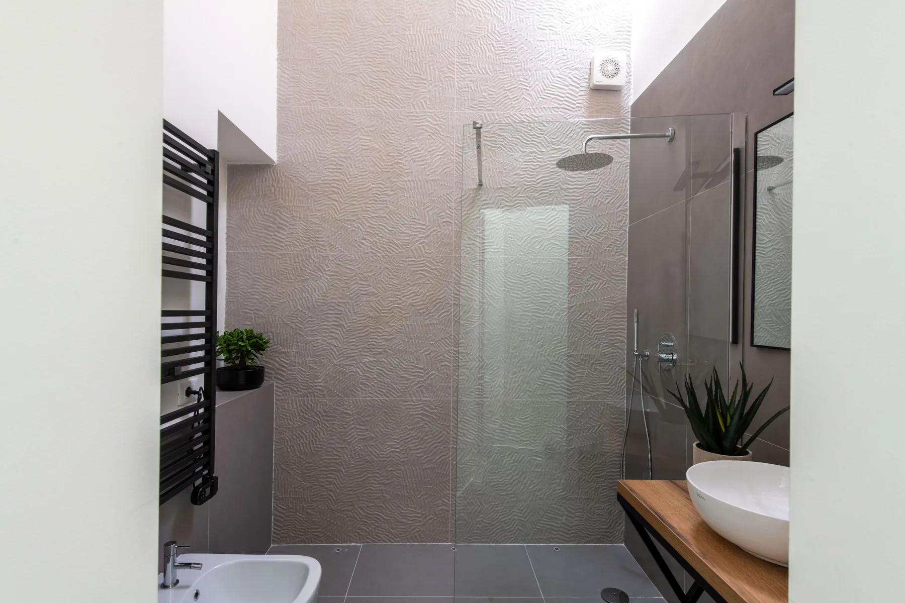 A modern bathroom with a glass shower and a wood vanity.