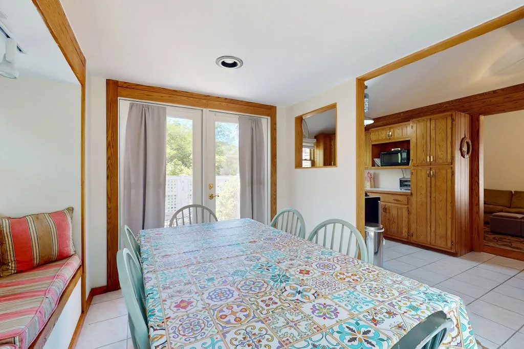 A dining area with a patterned tablecloth and sliding glass doors.