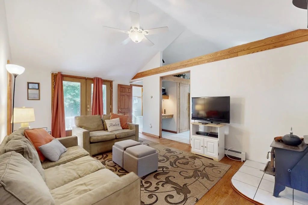 A living room with seating, a television, and a patterned rug.