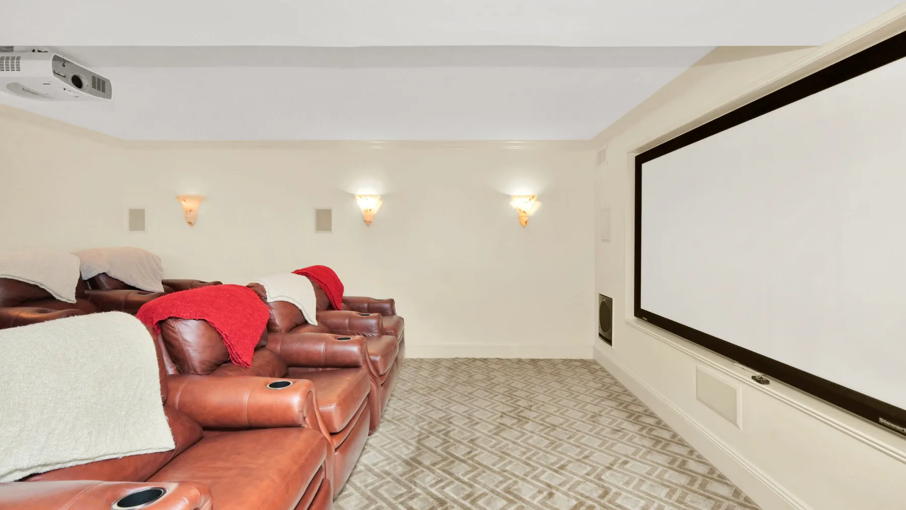 Una sala de cine en casa con asientos orientados hacia una gran pantalla de proyección.