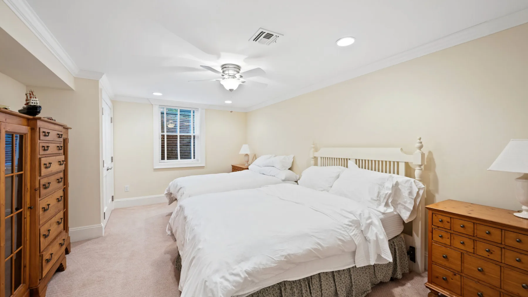 Dormitorio con una cama grande, ropa de cama blanca y cómodas de madera.