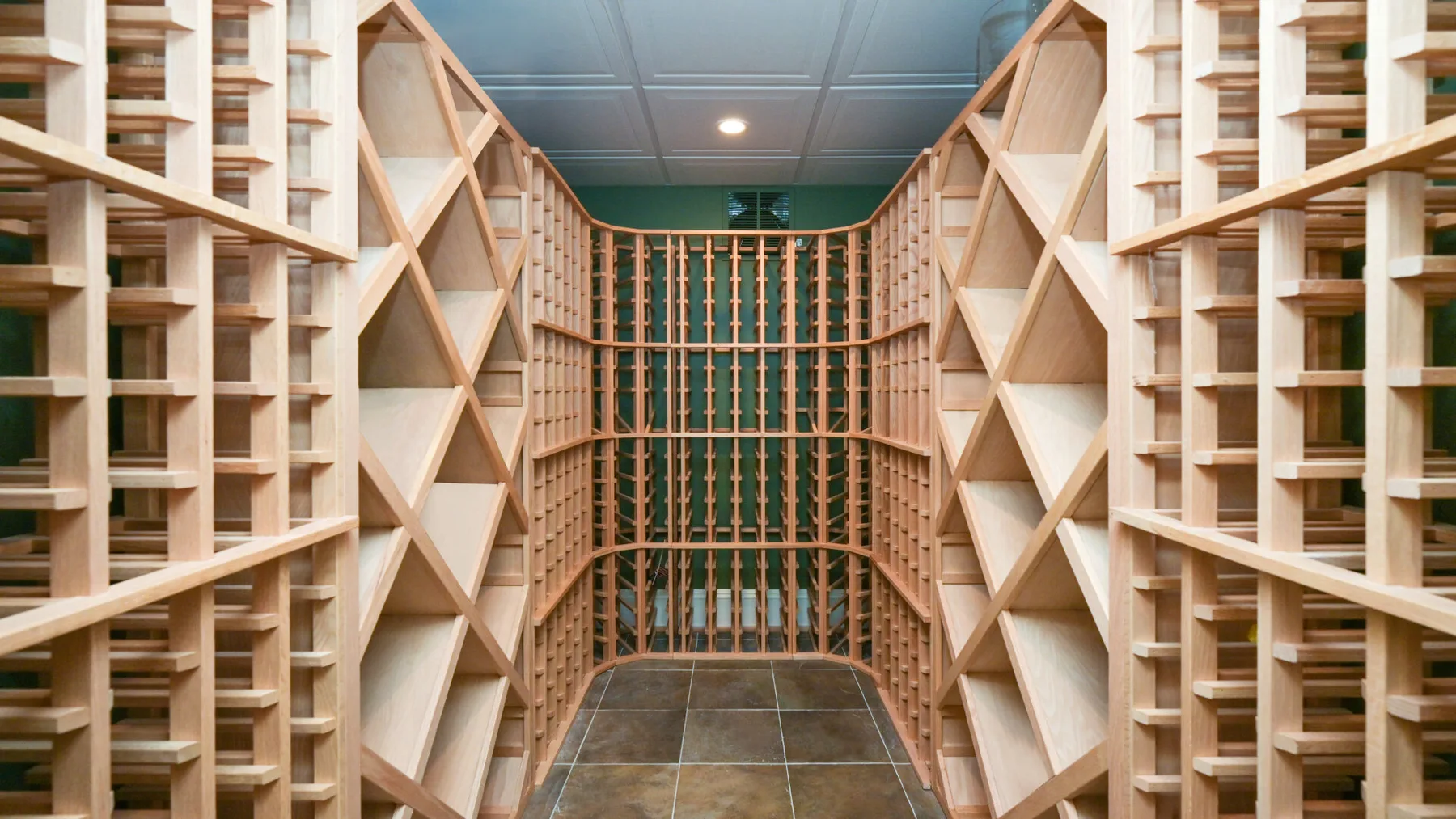 Una sala con estanterías de madera y una estructura central para guardar botellas.