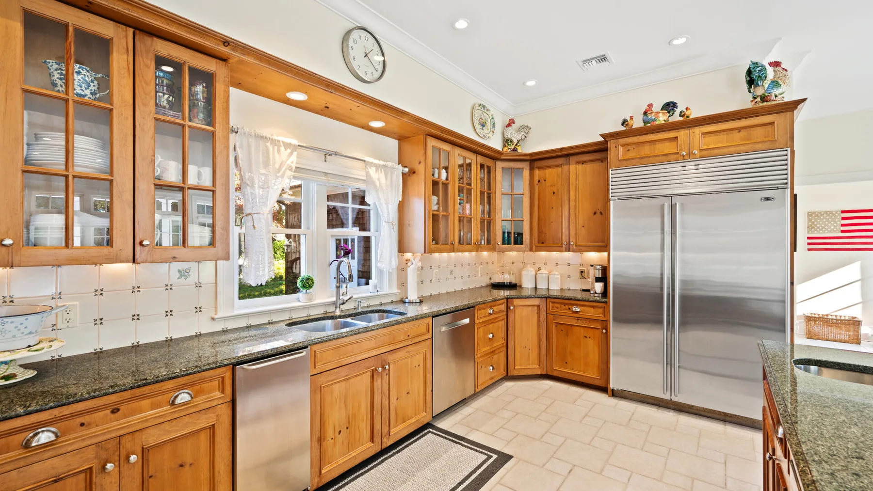 Una cocina luminosa con gabinetes de madera y un refrigerador grande de acero inoxidable.