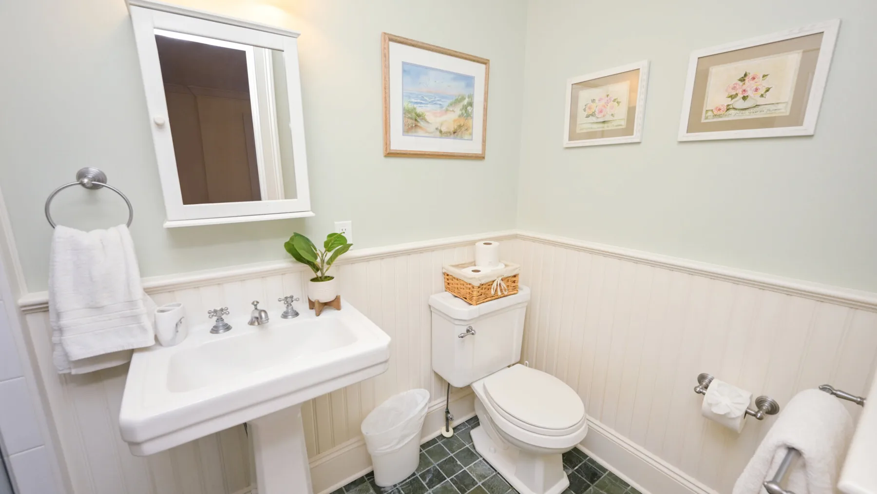 Un baño con lavabo, inodoro y cuadros en las paredes.