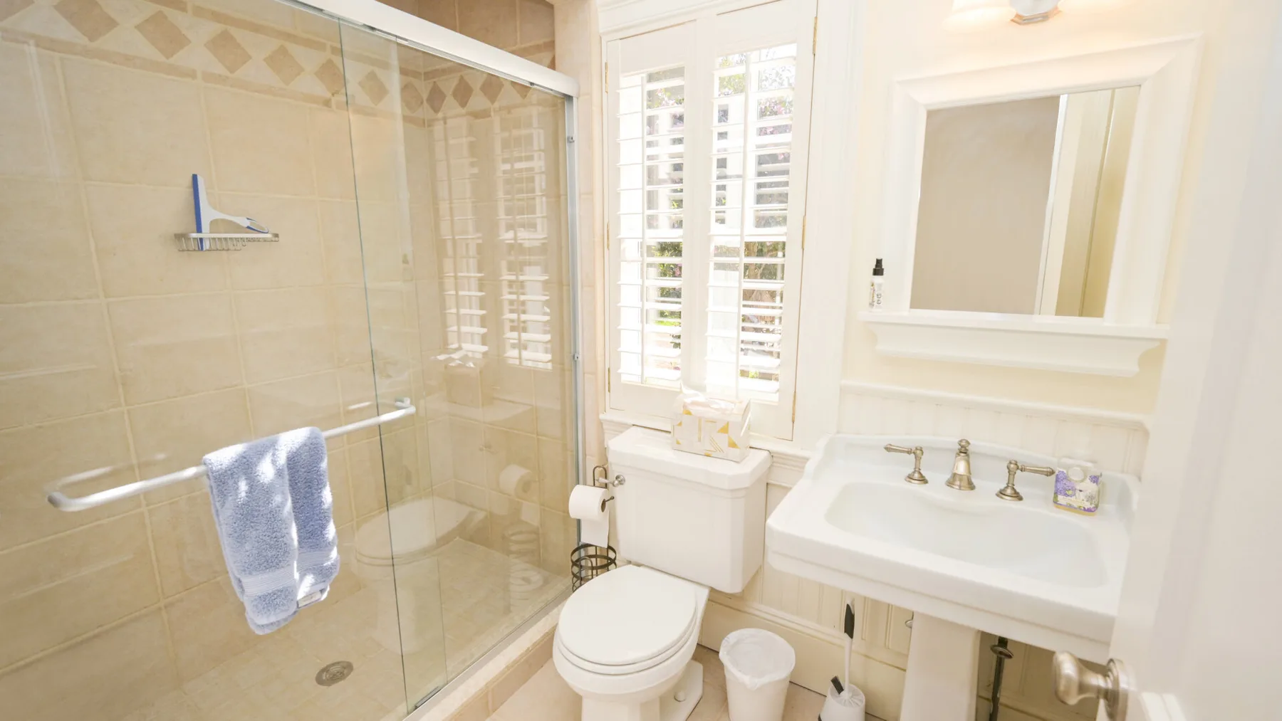 Un baño luminoso con ducha de vidrio, inodoro y lavabo.