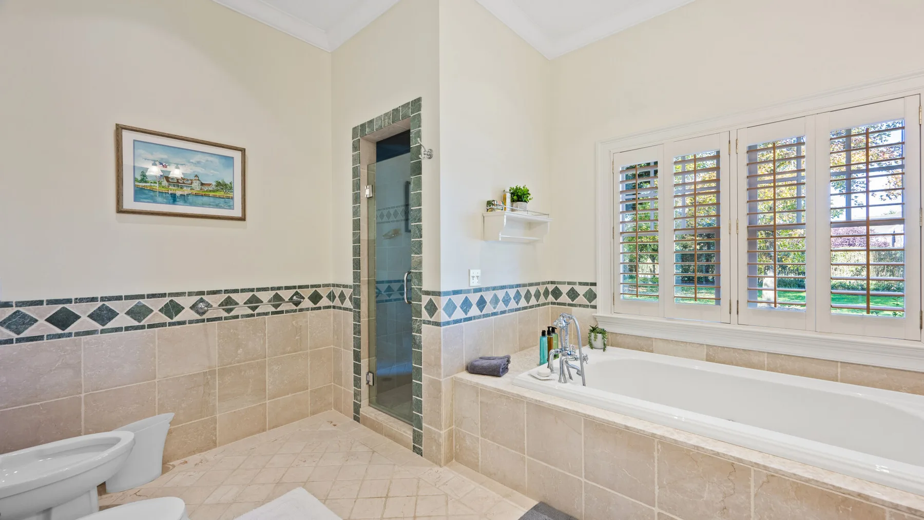 Un baño alicatado con bañera, ducha y ventanas con contraventanas.