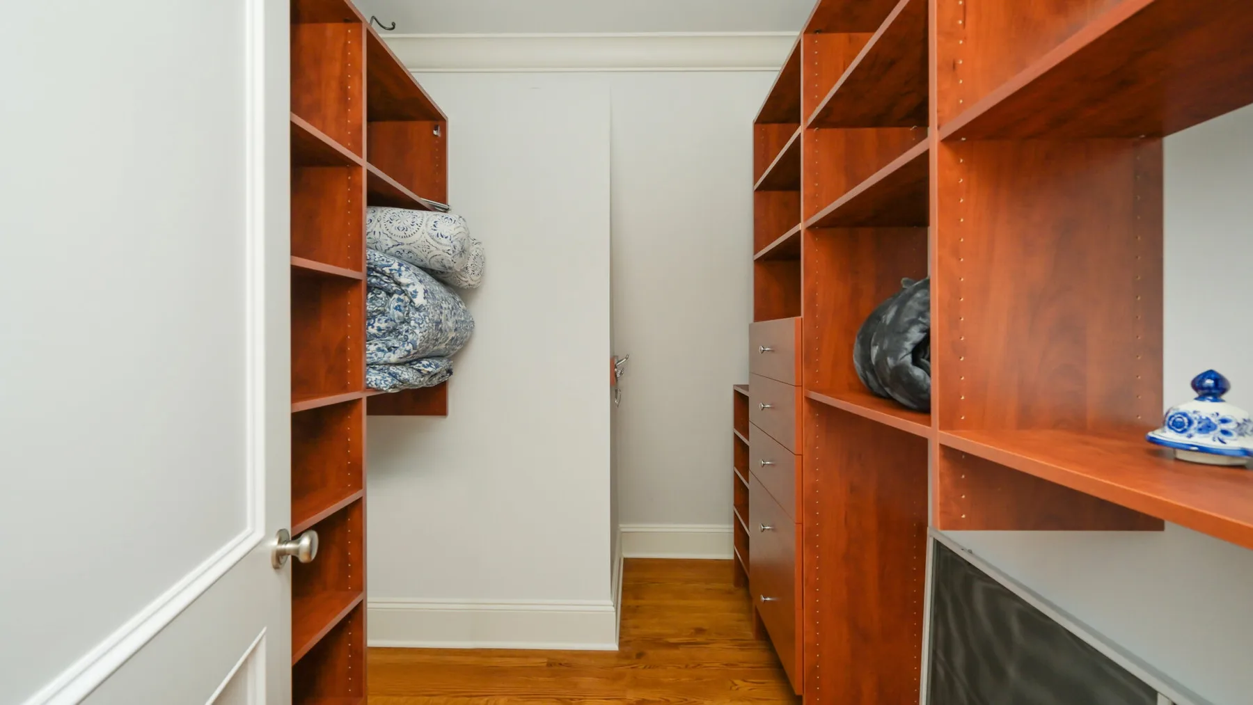 Un cuarto de almacenamiento con estanterías y ropa de cama doblada.