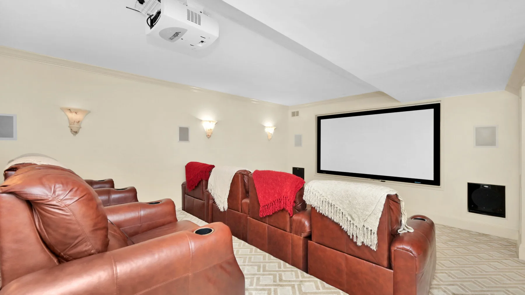 Una sala de cine en casa con asientos de cuero orientados hacia una gran pantalla de proyección.