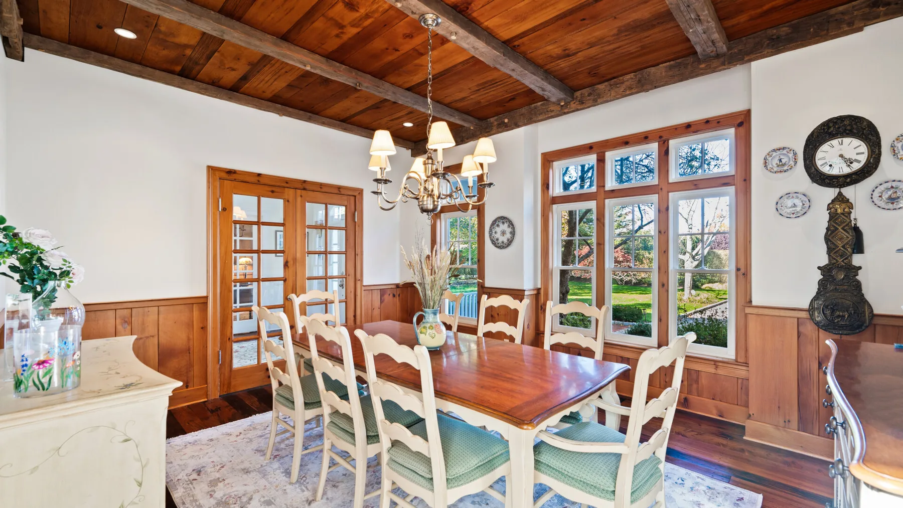 Un comedor con una mesa larga de madera y ventanas grandes.