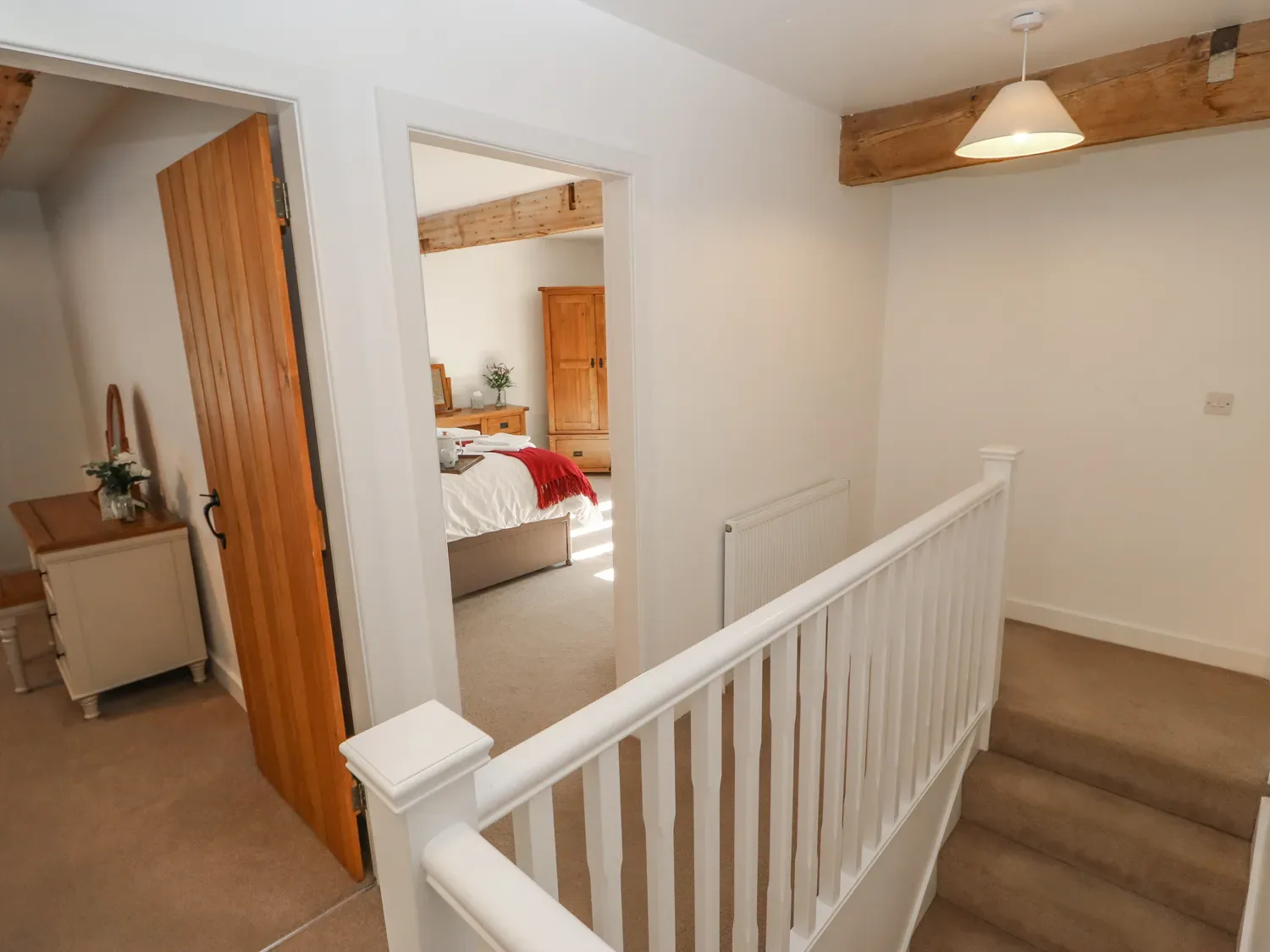 A hallway with wooden doors leading to a bedroom and a room with a dressing table at The Cottage Beeston Hall Ripponden