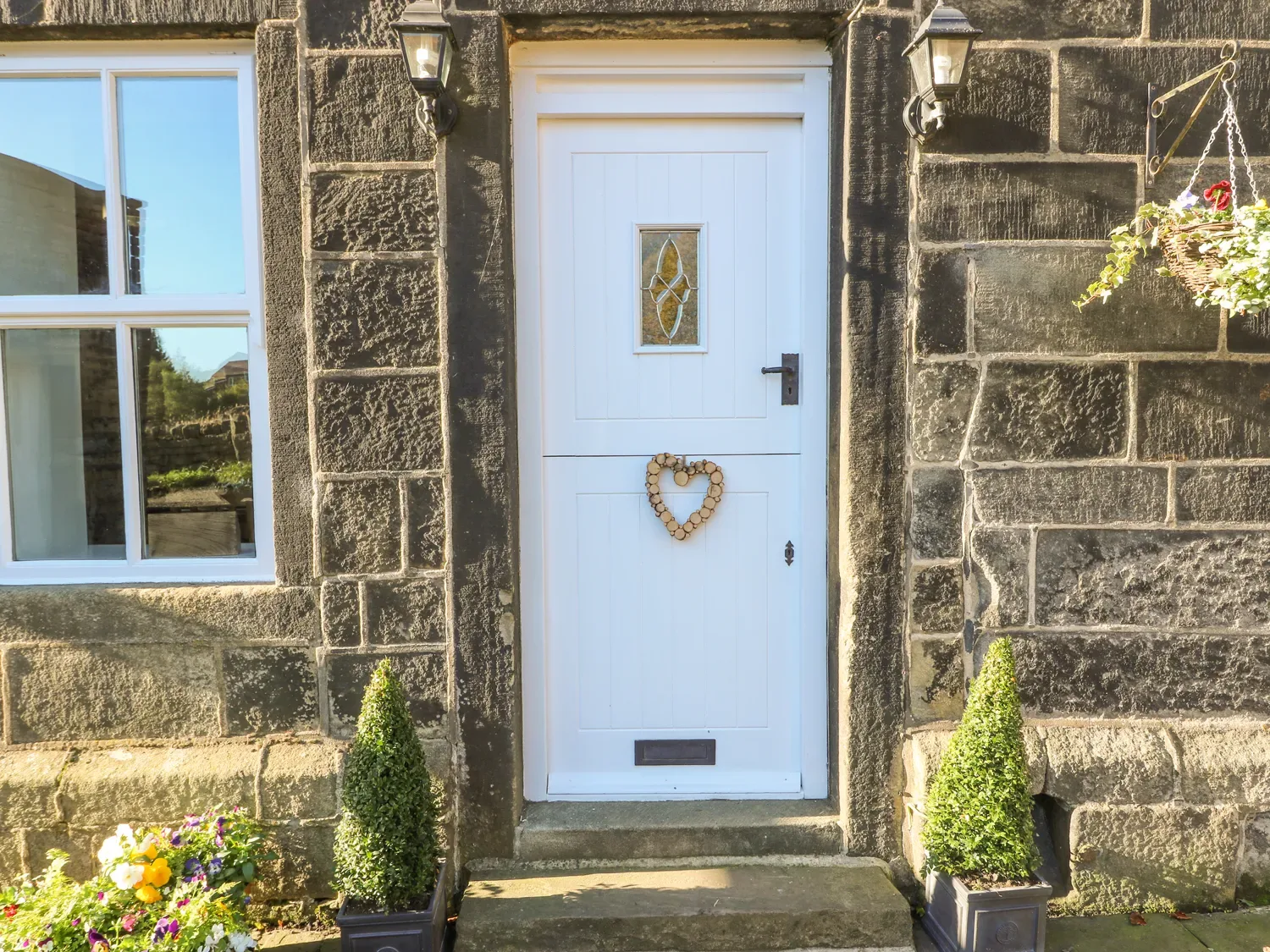 A white entrance door with a small window and heart decoration set in a stone exterior.