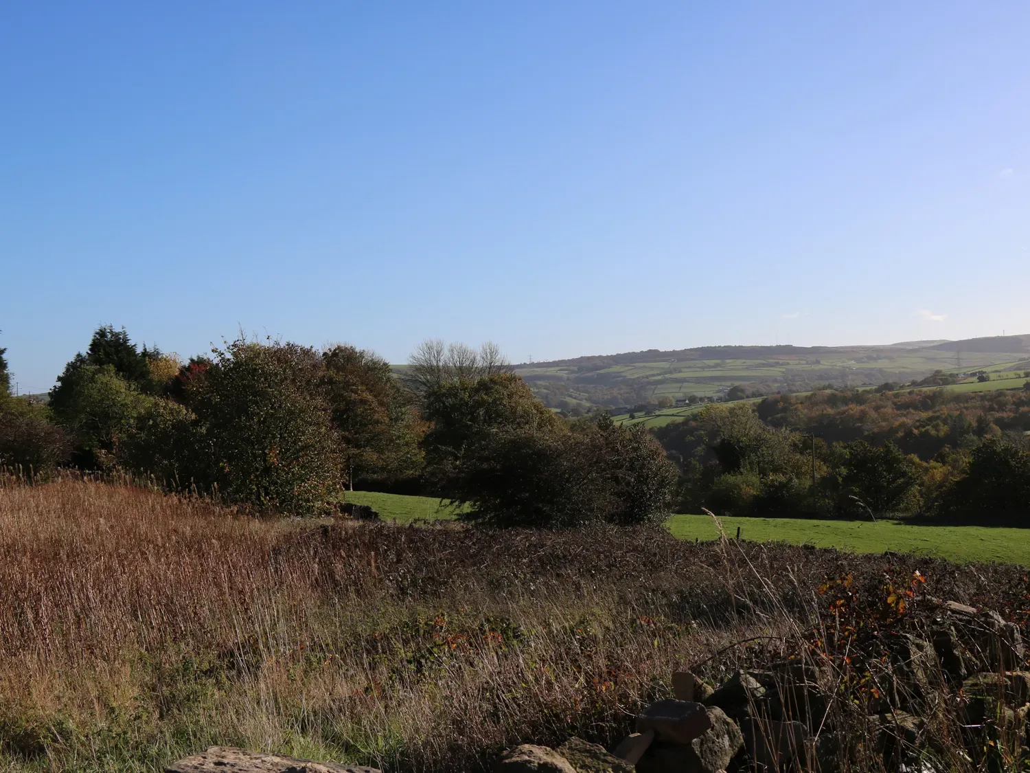 A rural landscape with fields trees and hills under a clear blue sky at The Cottage Beeston Hall in Ripponden