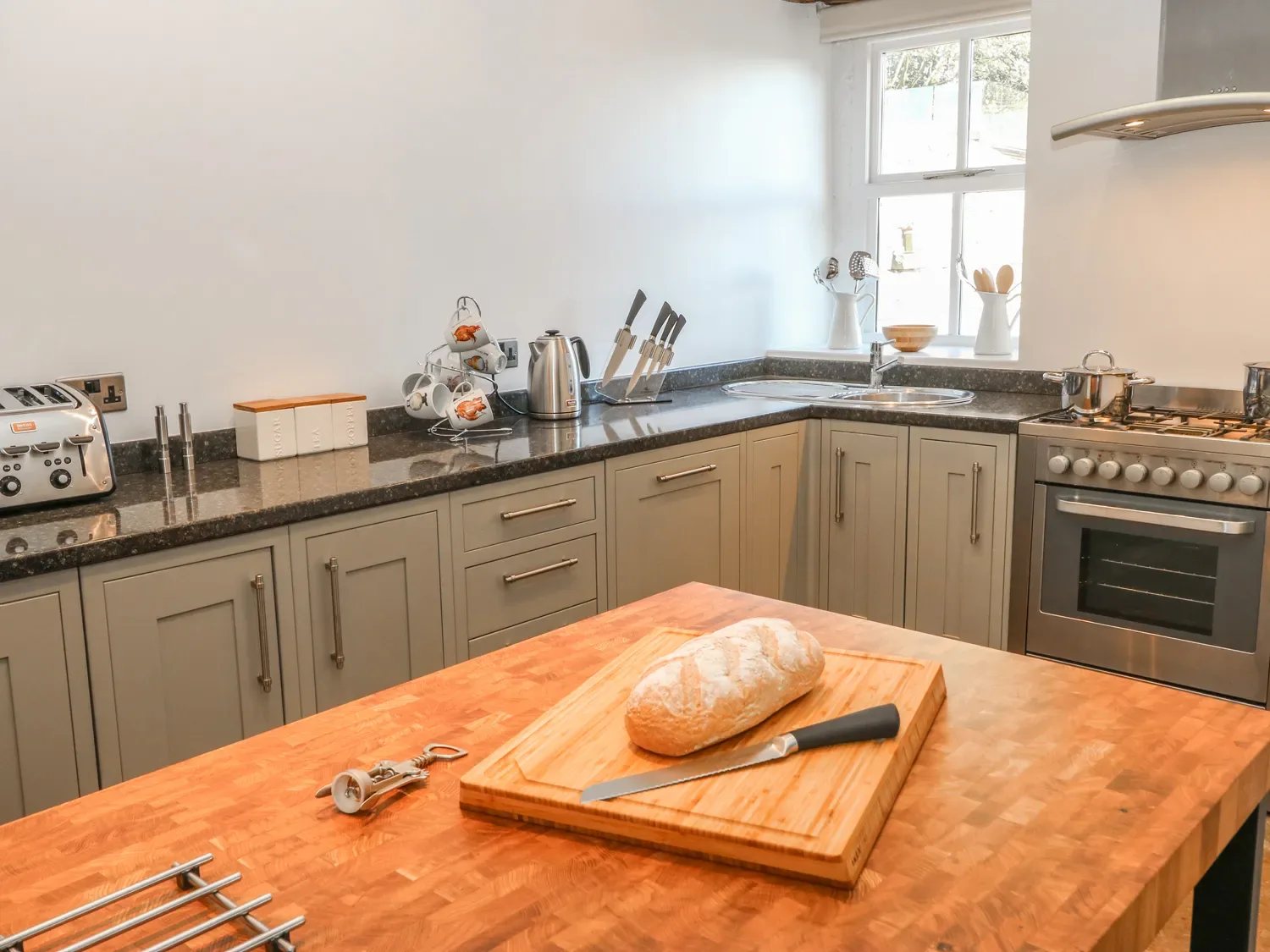 A kitchen with a bread loaf and knife on a wooden island.
