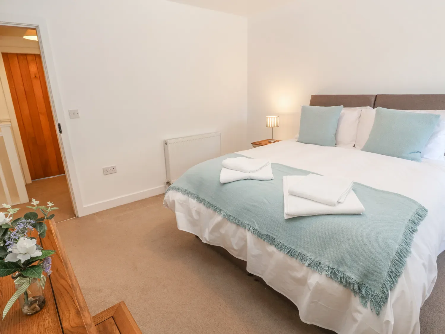 A bedroom with a neatly made bed and folded towels.