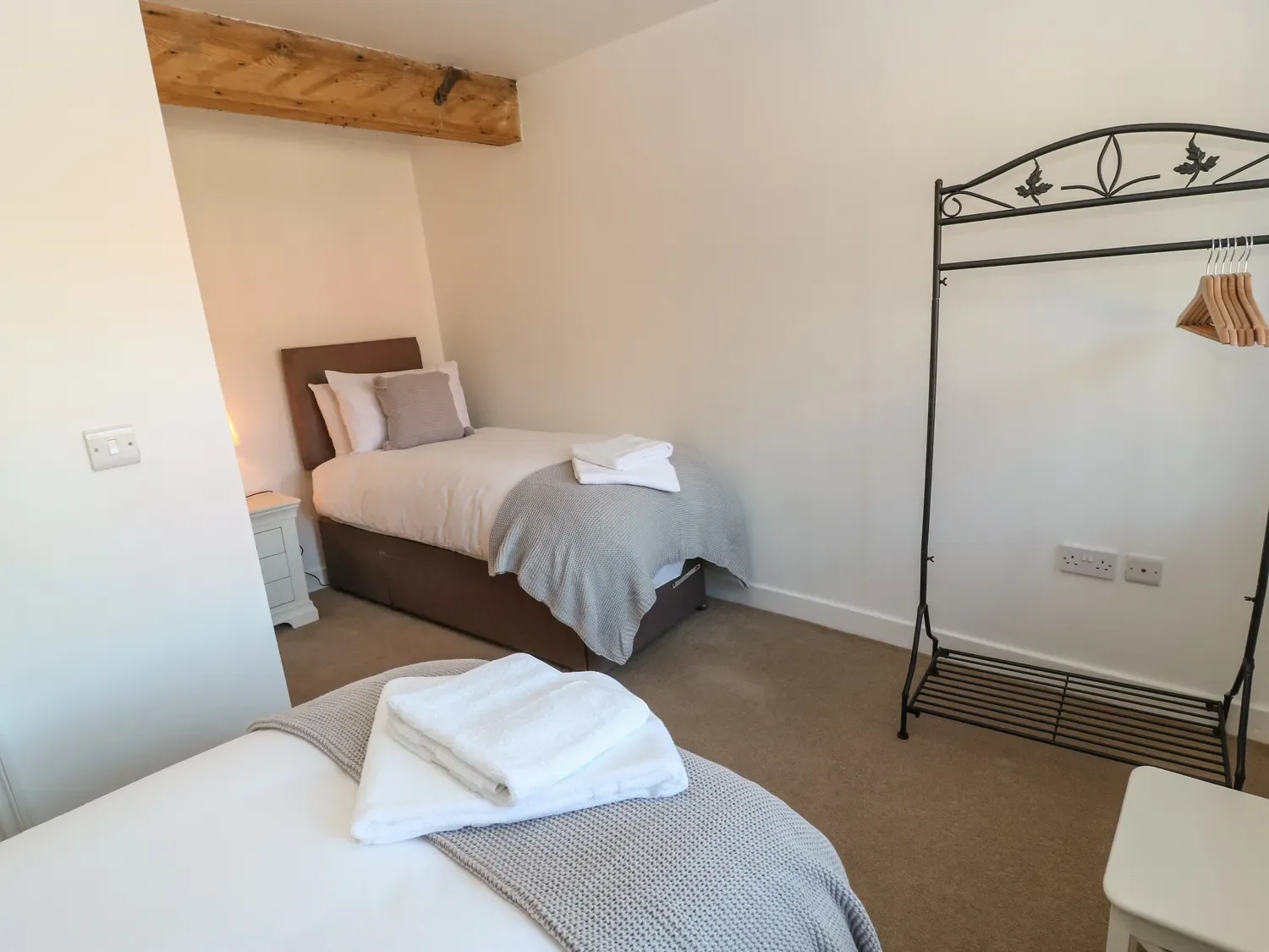 A bedroom with two single beds a nightstand and a metal clothes rack at The Cottage Beeston Hall in Ripponden