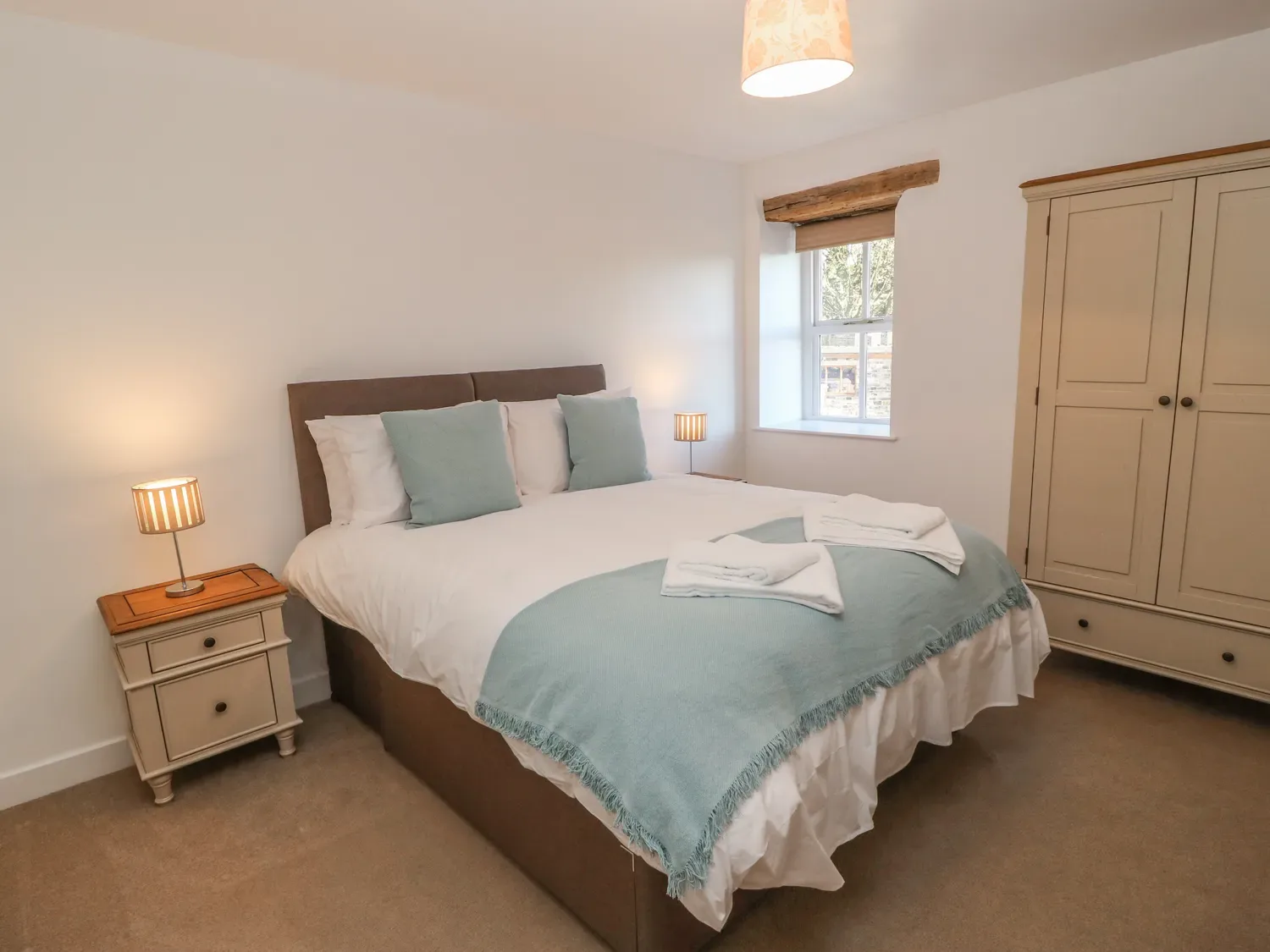 A bedroom with a double bed bedside tables lamps a window and a wardrobe at The Cottage Beeston Hall Ripponden