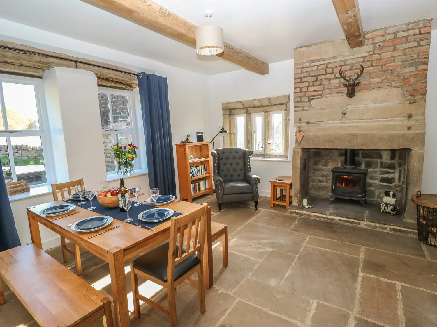 A dining area with a set wooden table and a fireplace with a stove.