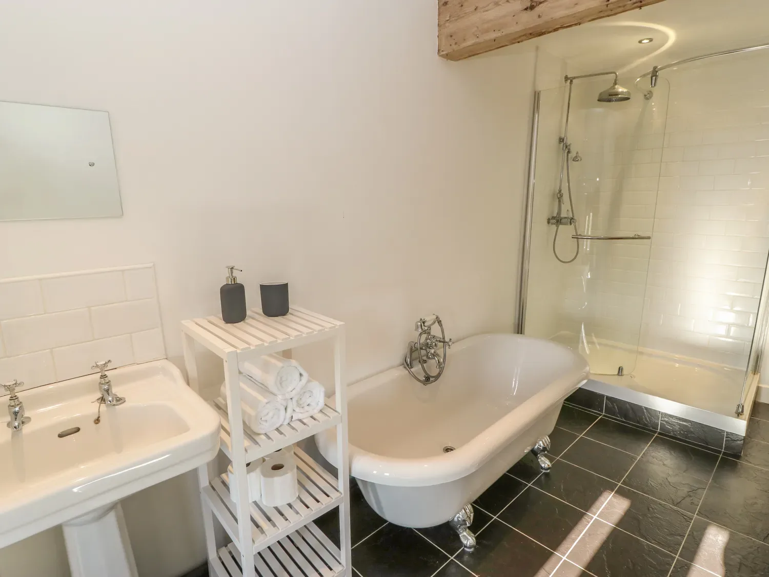 A bathroom with a pedestal sink, clawfoot bathtub, and glass shower.