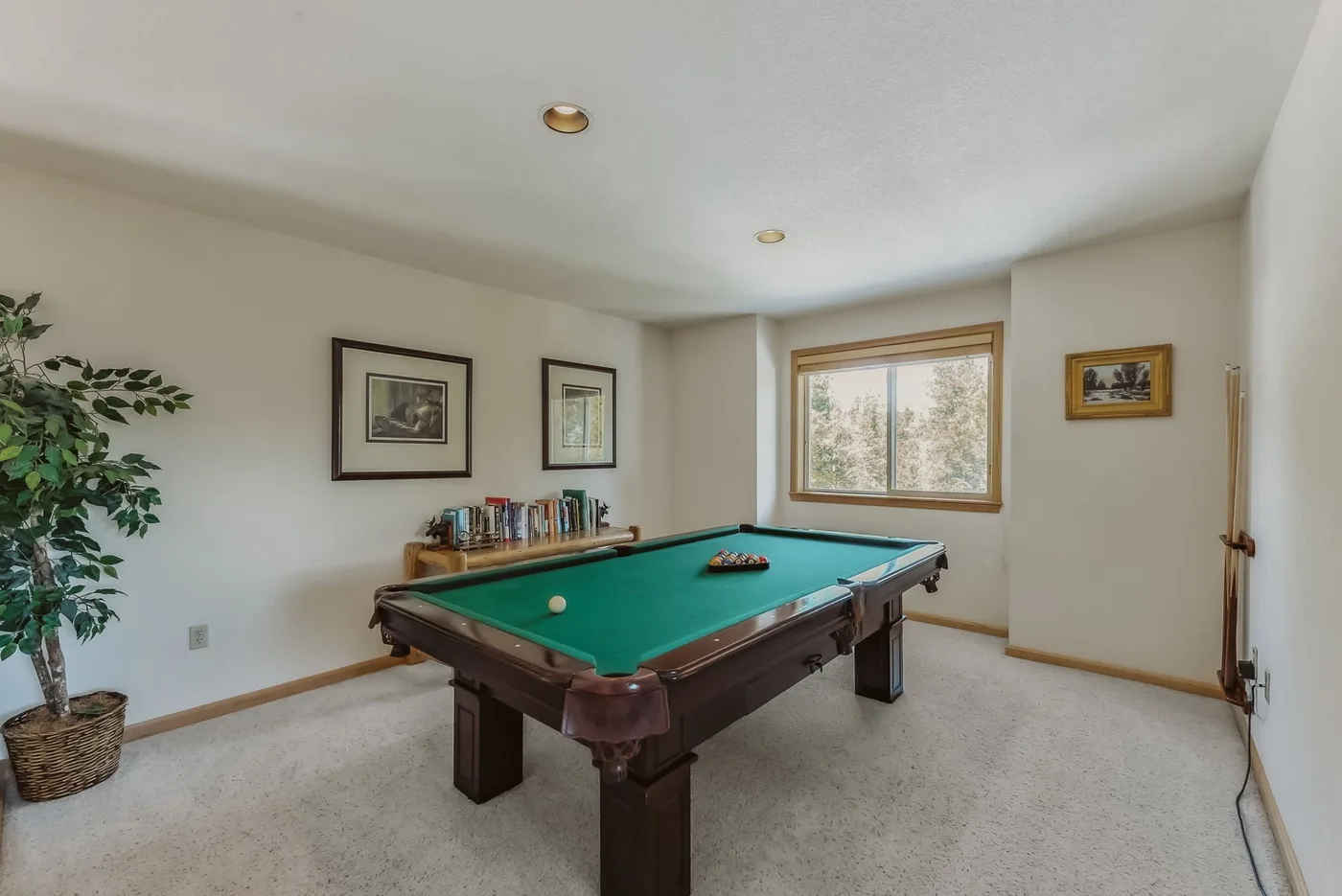 A game room with a green-felt pool table and framed pictures on the walls.