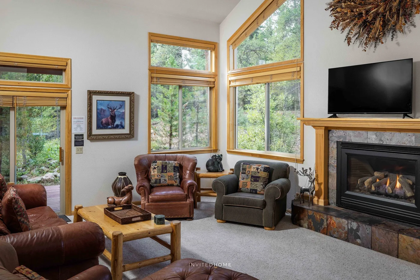 A living room with leather seating, tall windows, and a fireplace.