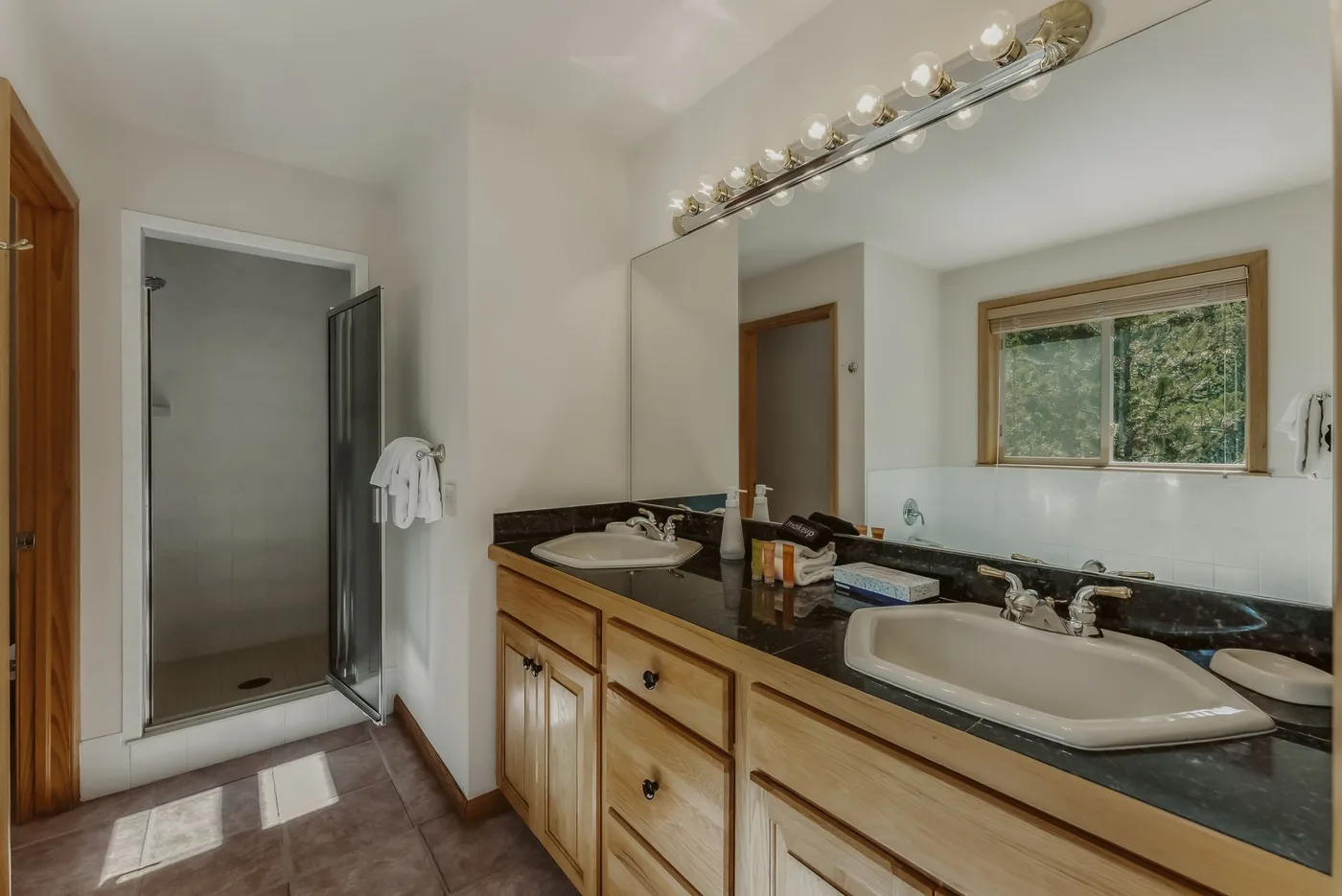 A bathroom with a long vanity, mirror, and glass shower.