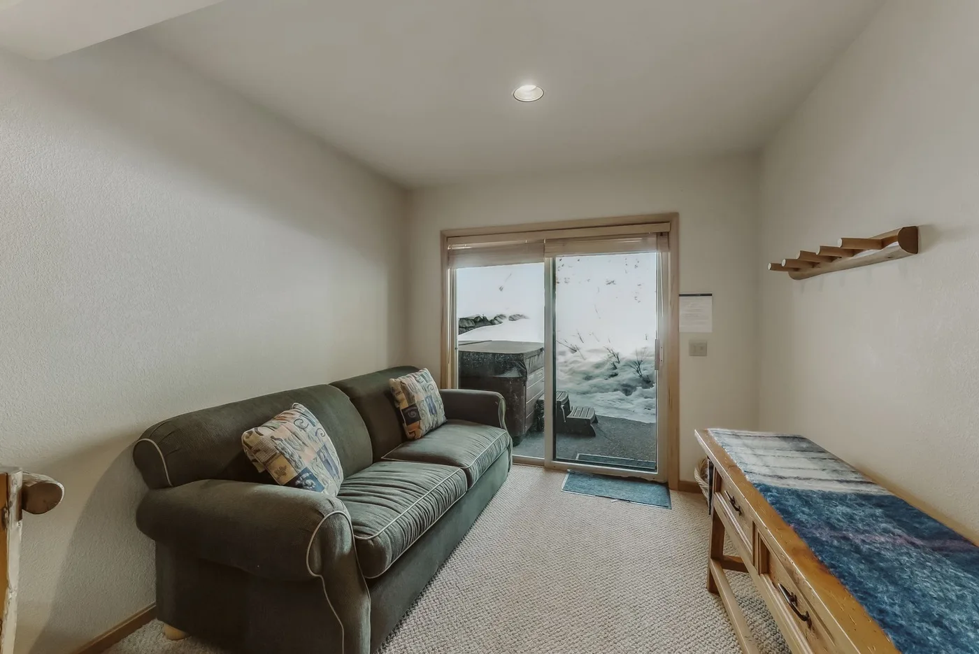 A bedroom with a seating area, a bed, and glass doors opening to a view of the water.