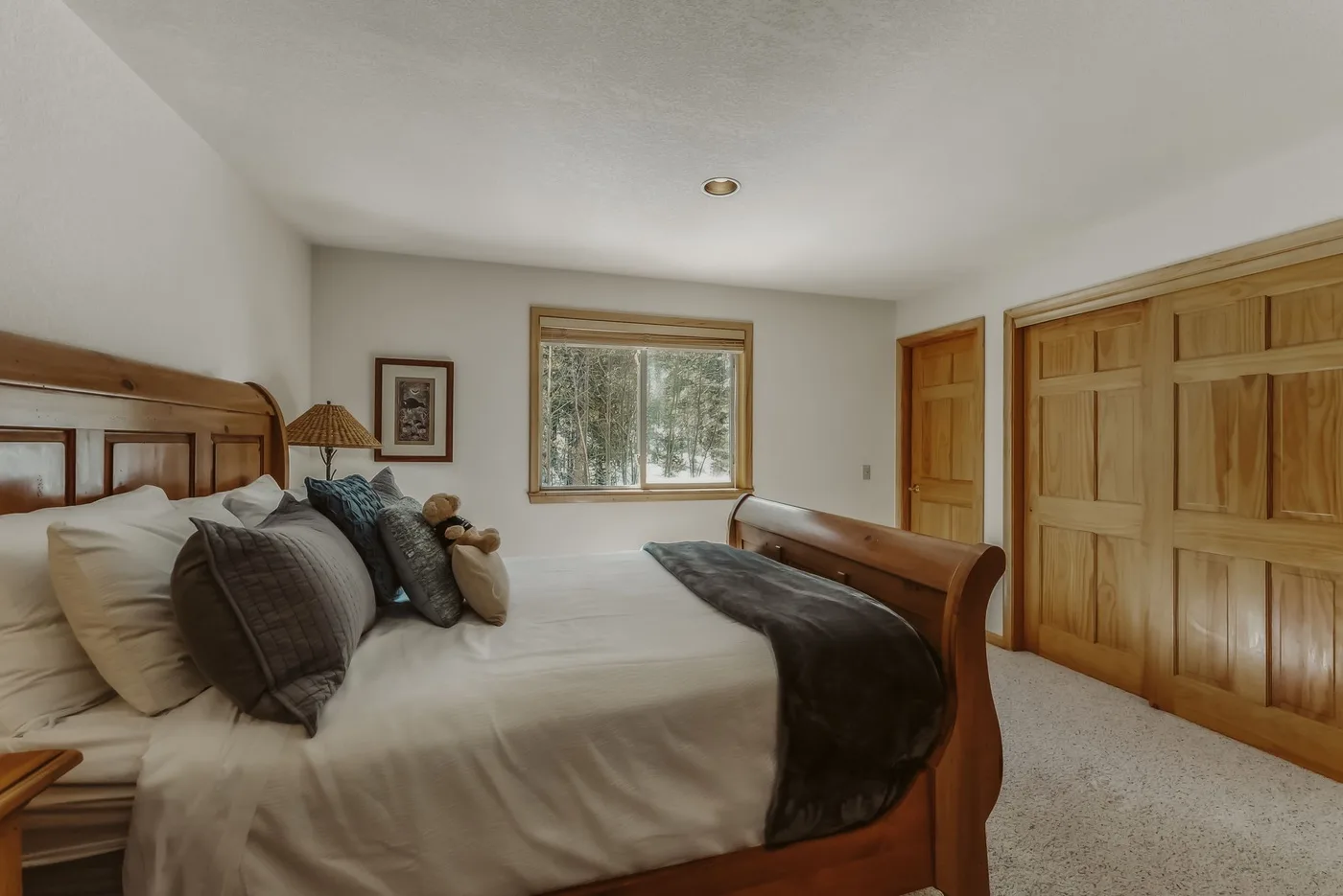 A bedroom with a large bed, wooden furniture, and a window.