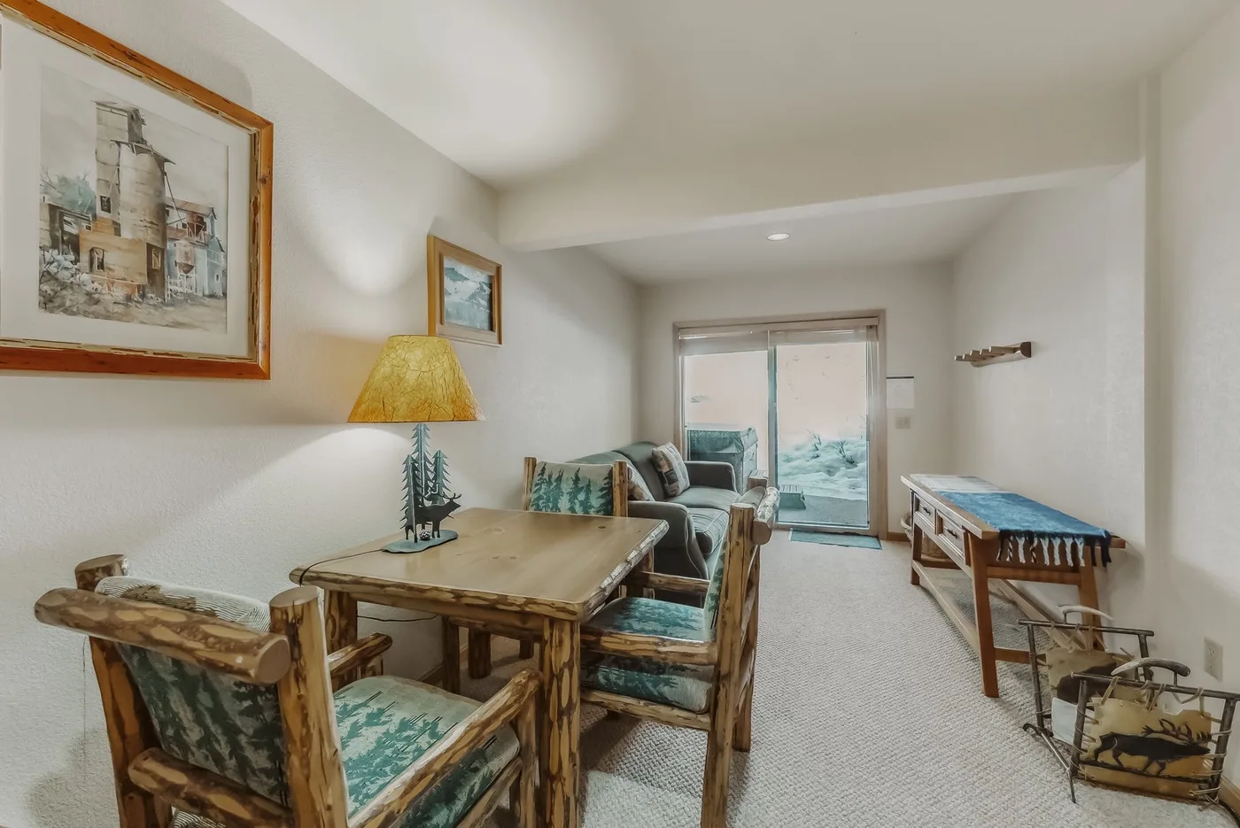 A living room with a wooden dining table and seating beside a glass door.