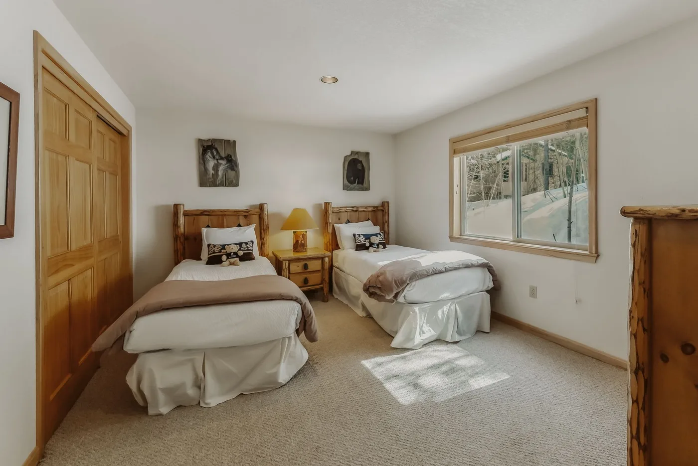 A bedroom with two beds and a large window overlooking trees.