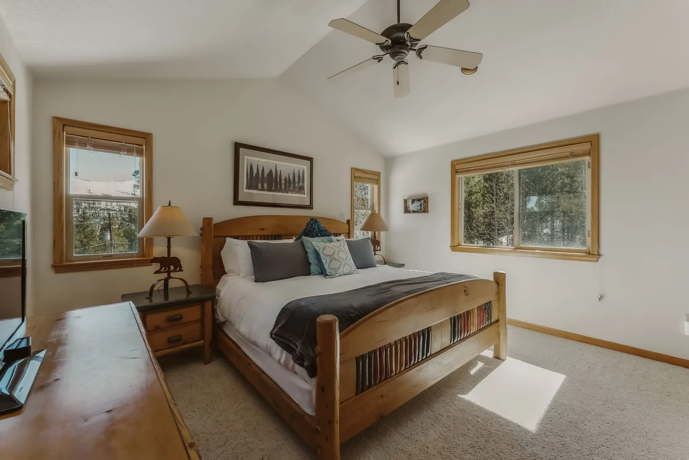A bedroom with a wooden bed, bedside tables, and windows.