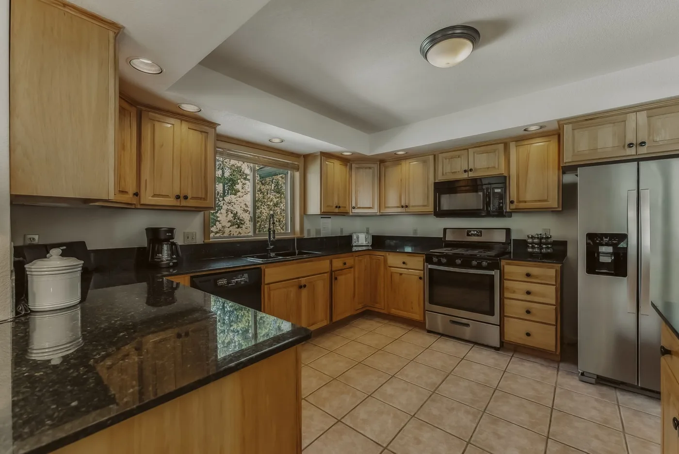 A kitchen with wooden cabinets, dark countertops, and stainless steel appliances.