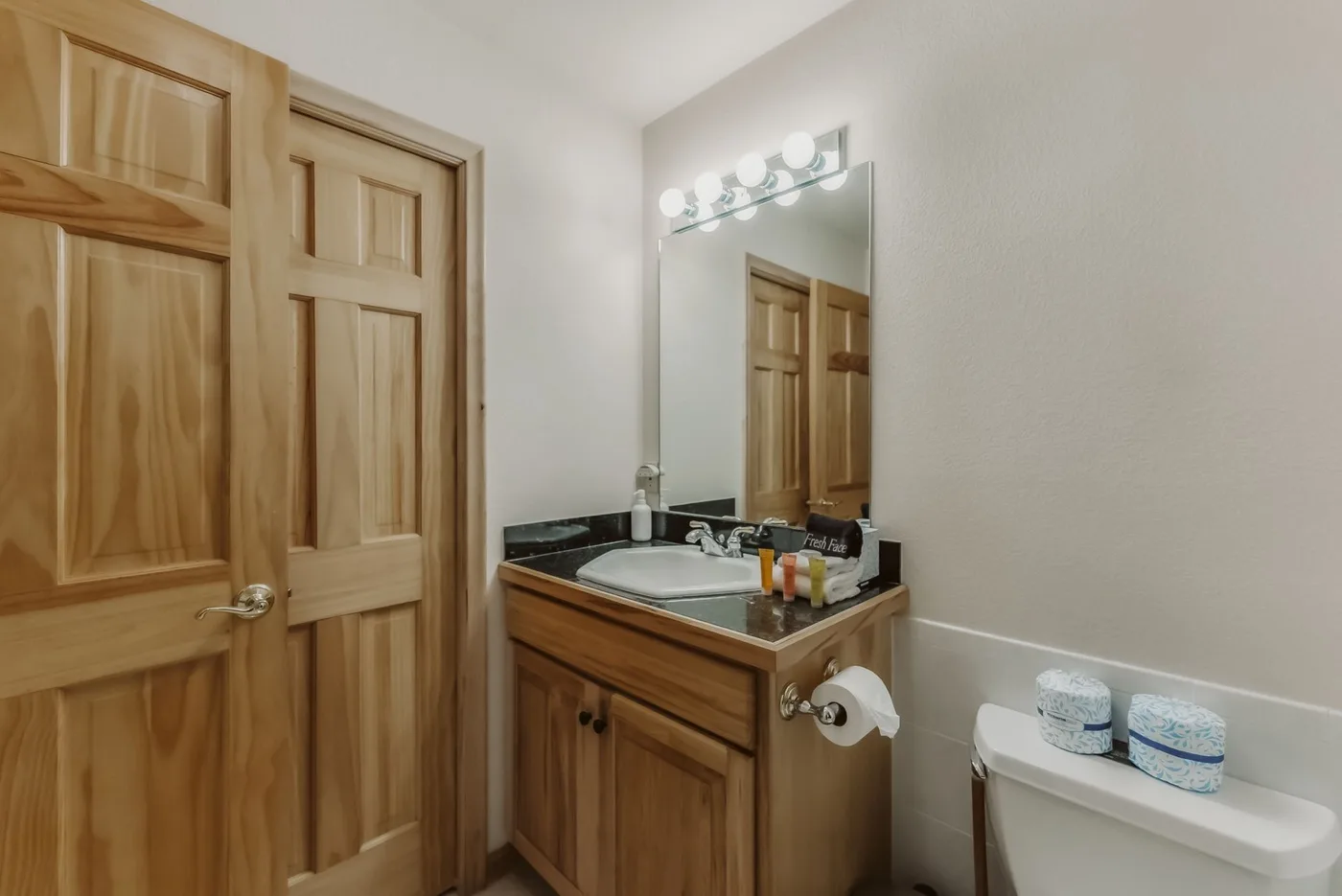 A bathroom vanity with a sink and mirror stands beside a wooden door.