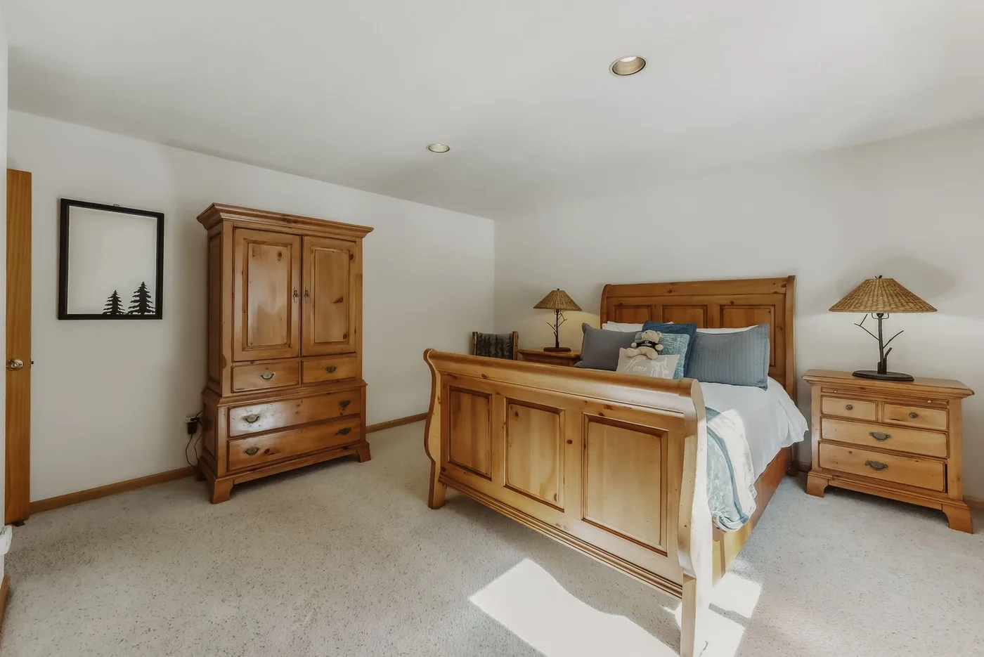 A bedroom with a wooden bed, matching dresser, and bedside tables.