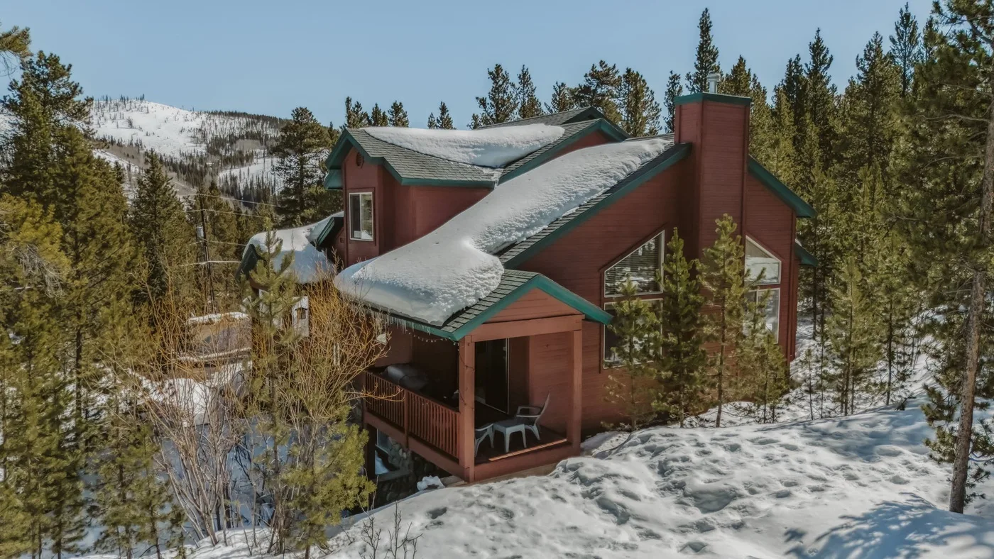 A red lodge stands among snow-covered trees on a mountain slope.