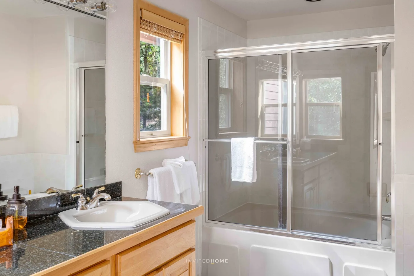 A bathroom with a sink, mirrored vanity, and glass shower enclosure.