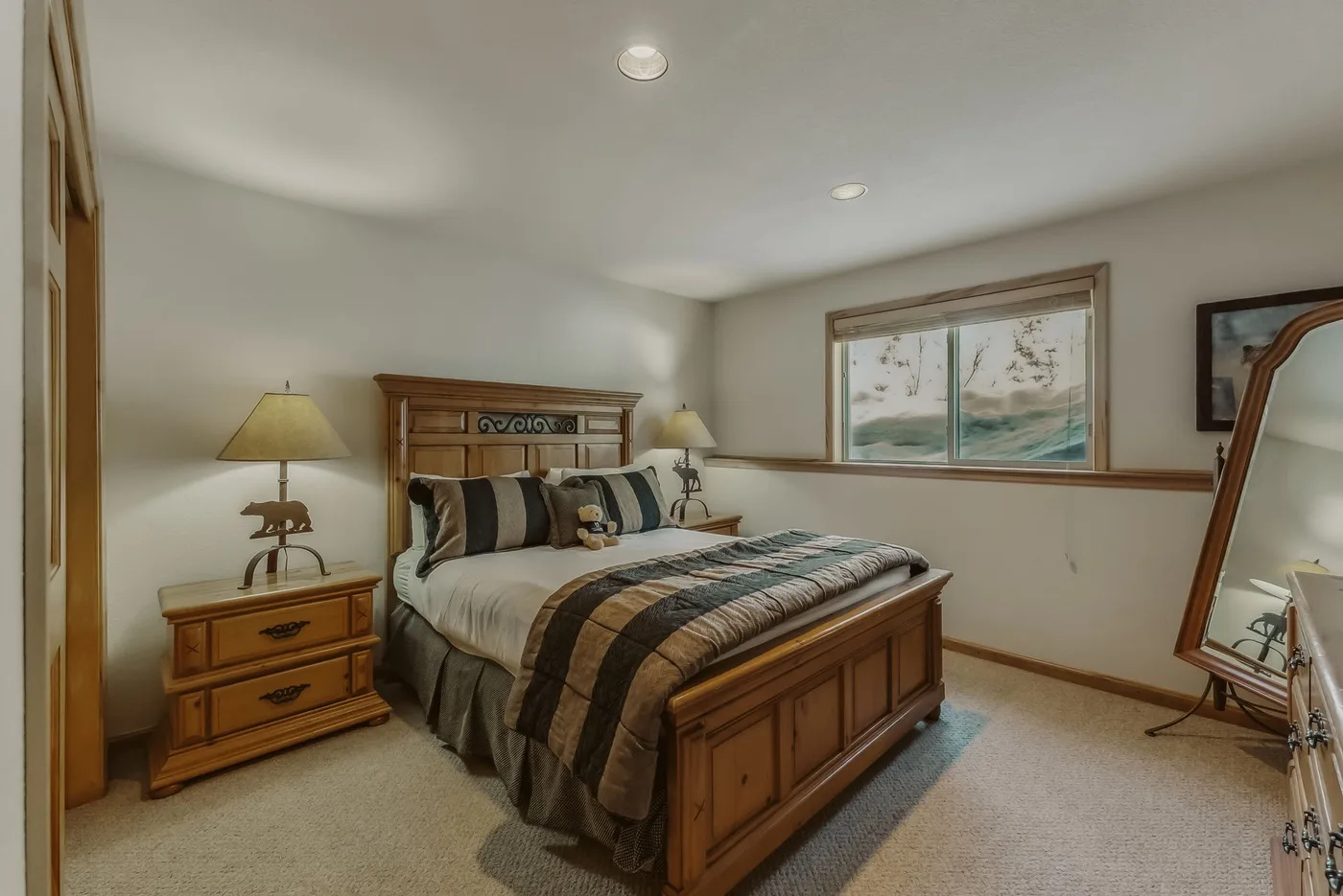 A bedroom with a wooden bed and framed artwork above the bed.