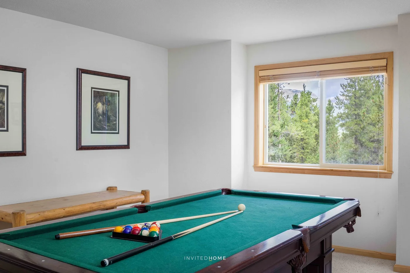 A billiards room with a pool table beneath a large window.