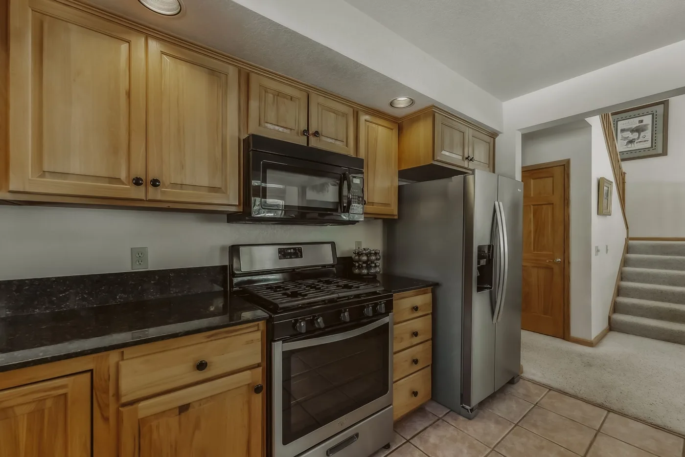 A kitchen with wooden cabinets, a stove, and a refrigerator.