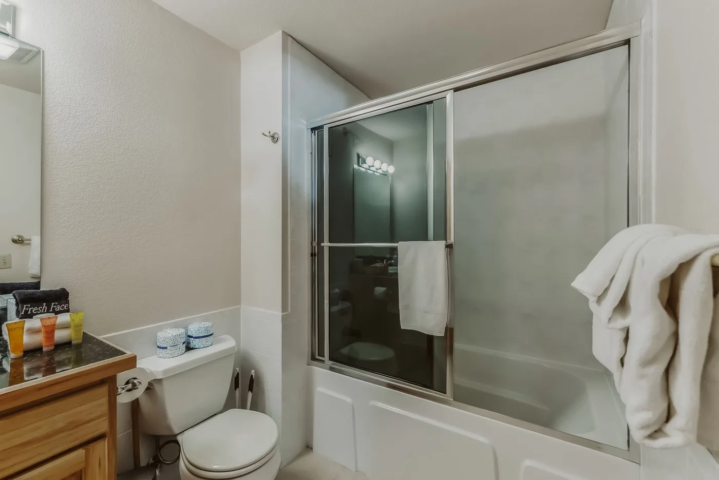 A bathroom with a bathtub, glass shower panels, and a toilet.