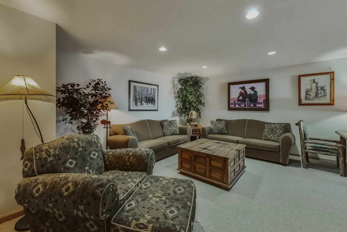 A living room with patterned seating, a wooden coffee table, and framed wall art.