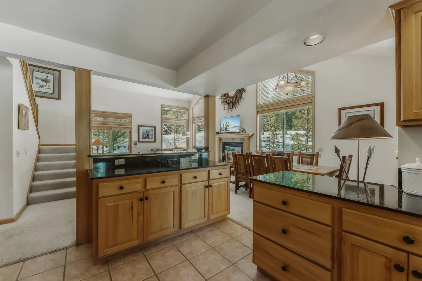 A kitchen with wooden cabinets and a counter opening onto a dining area.