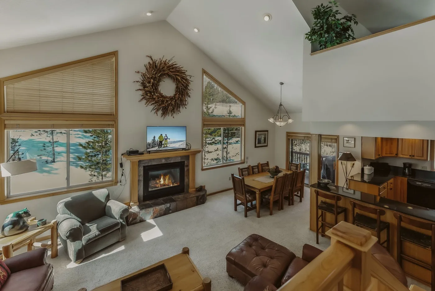 A vaulted living and dining area with a fireplace and large windows.