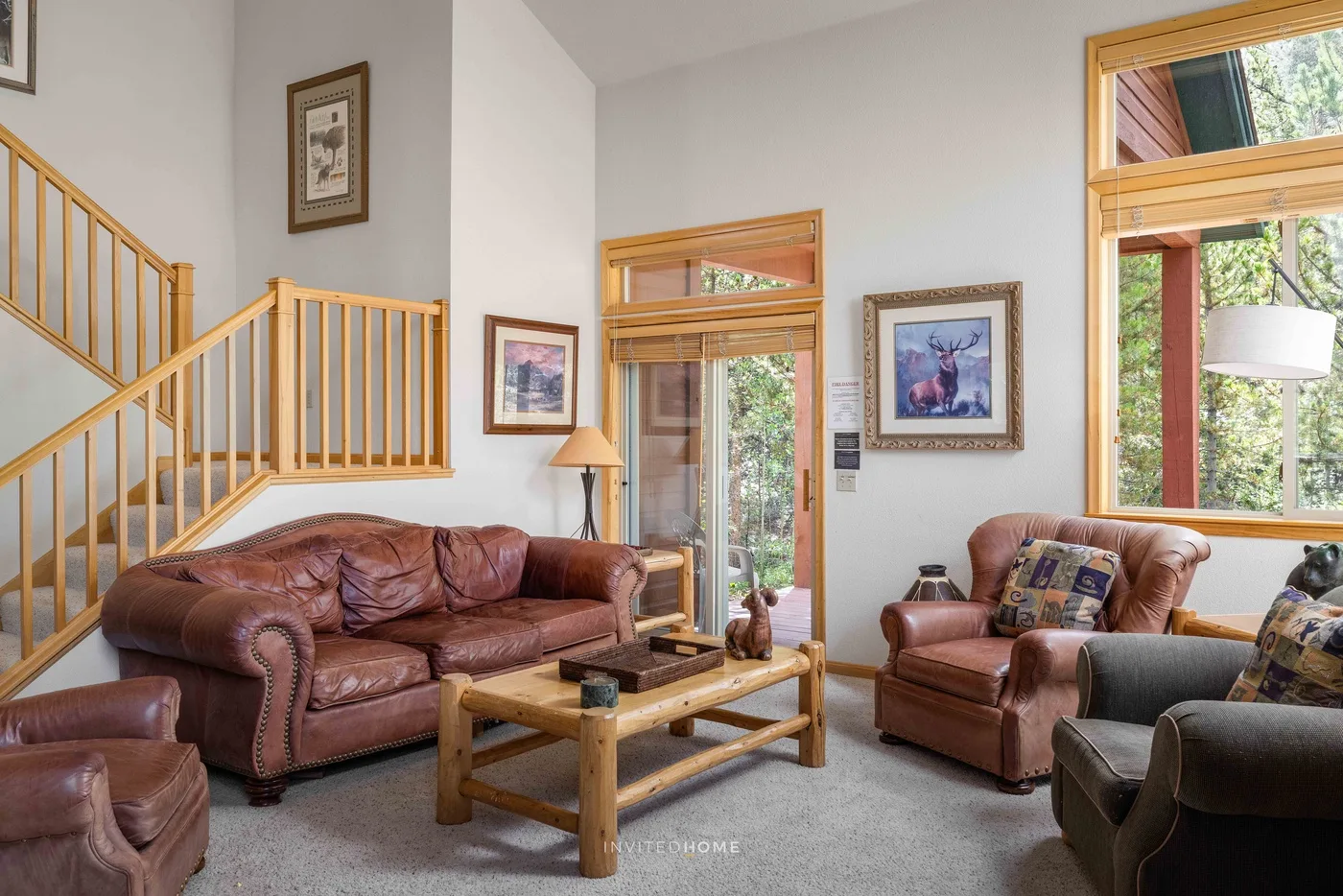 A living room with leather seating, a wooden coffee table, and a staircase.