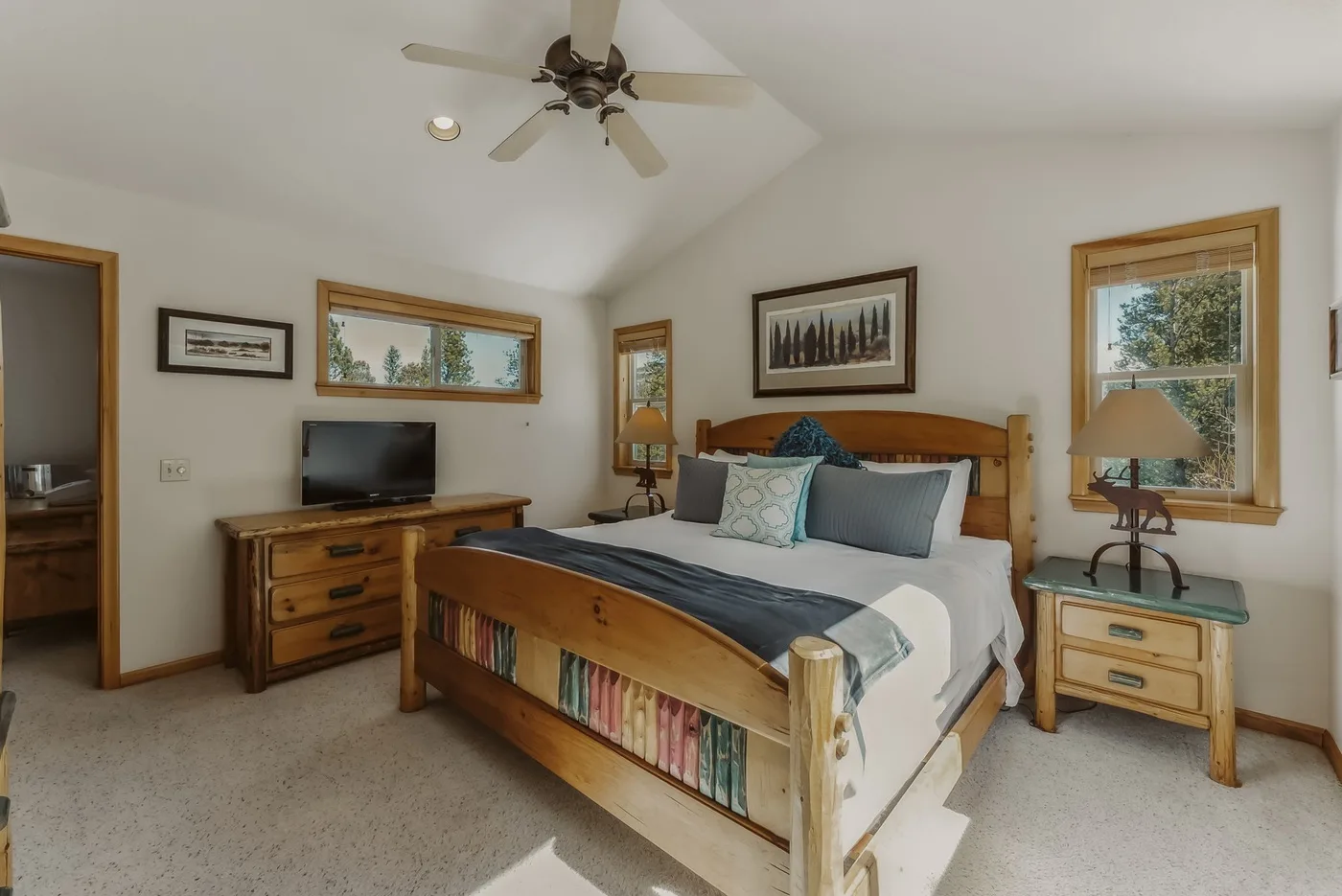 A bedroom with a wooden bed, television, and windows.