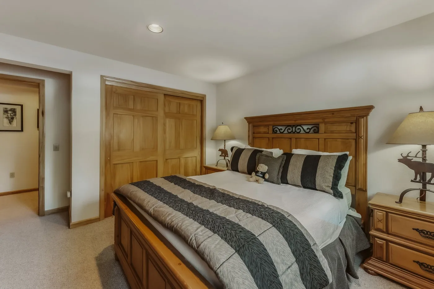 A bedroom with a wooden bed, striped bedding, and matching storage furniture.