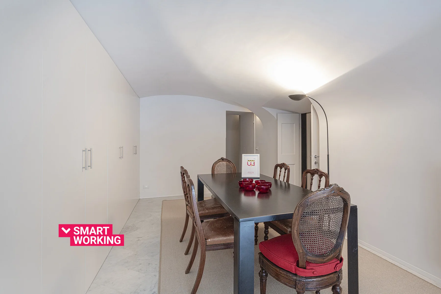Comedor con una mesa oscura y sillas bajo una lámpara de pie.