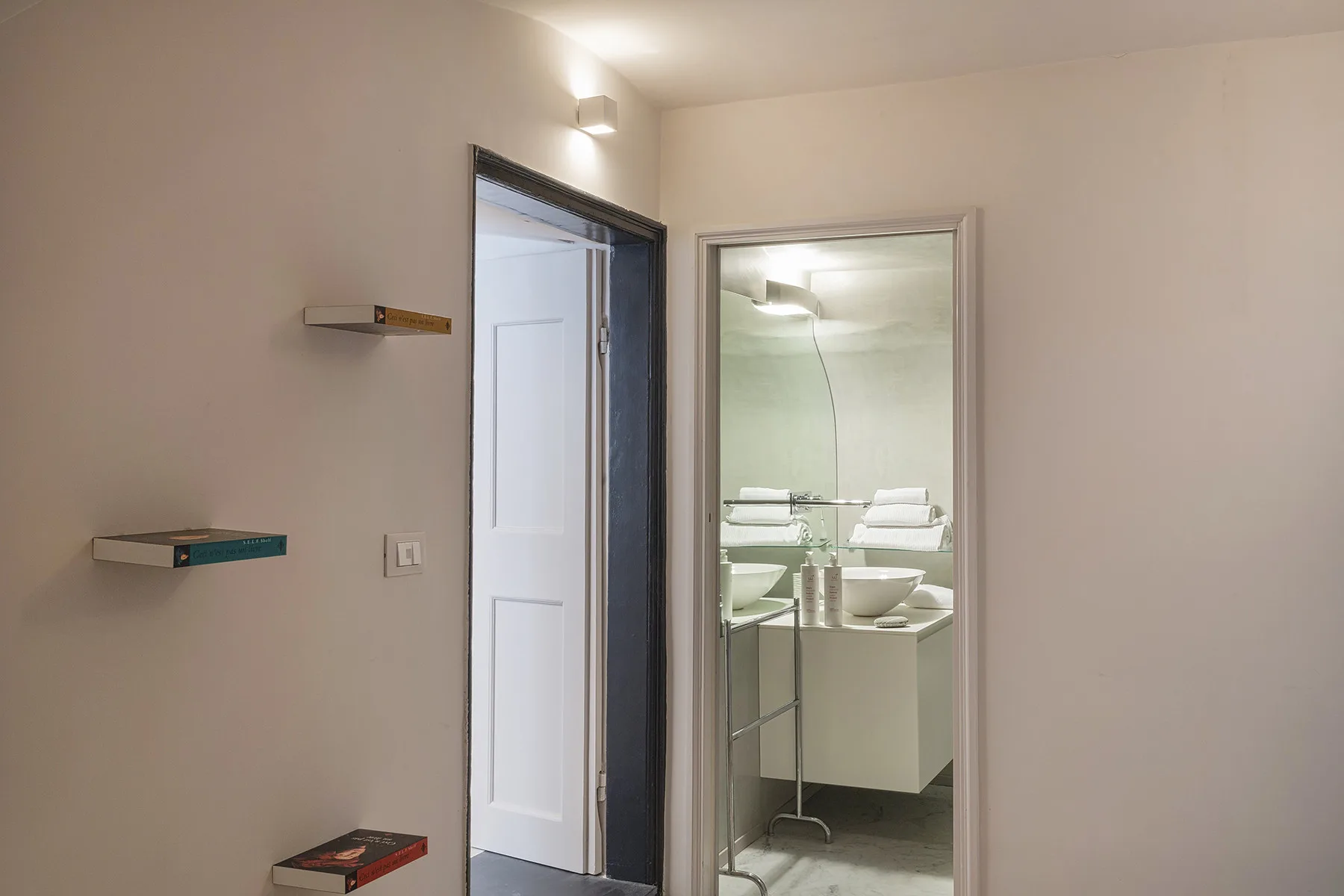 Se ven un lavabo y un espejo de baño a través de una puerta abierta.
