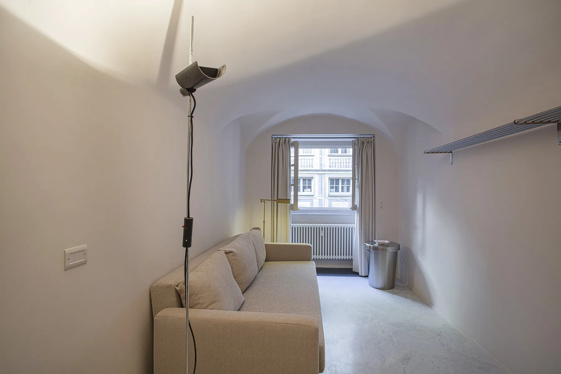 Una pequeña sala de estar con un sofá beige junto a una ventana.