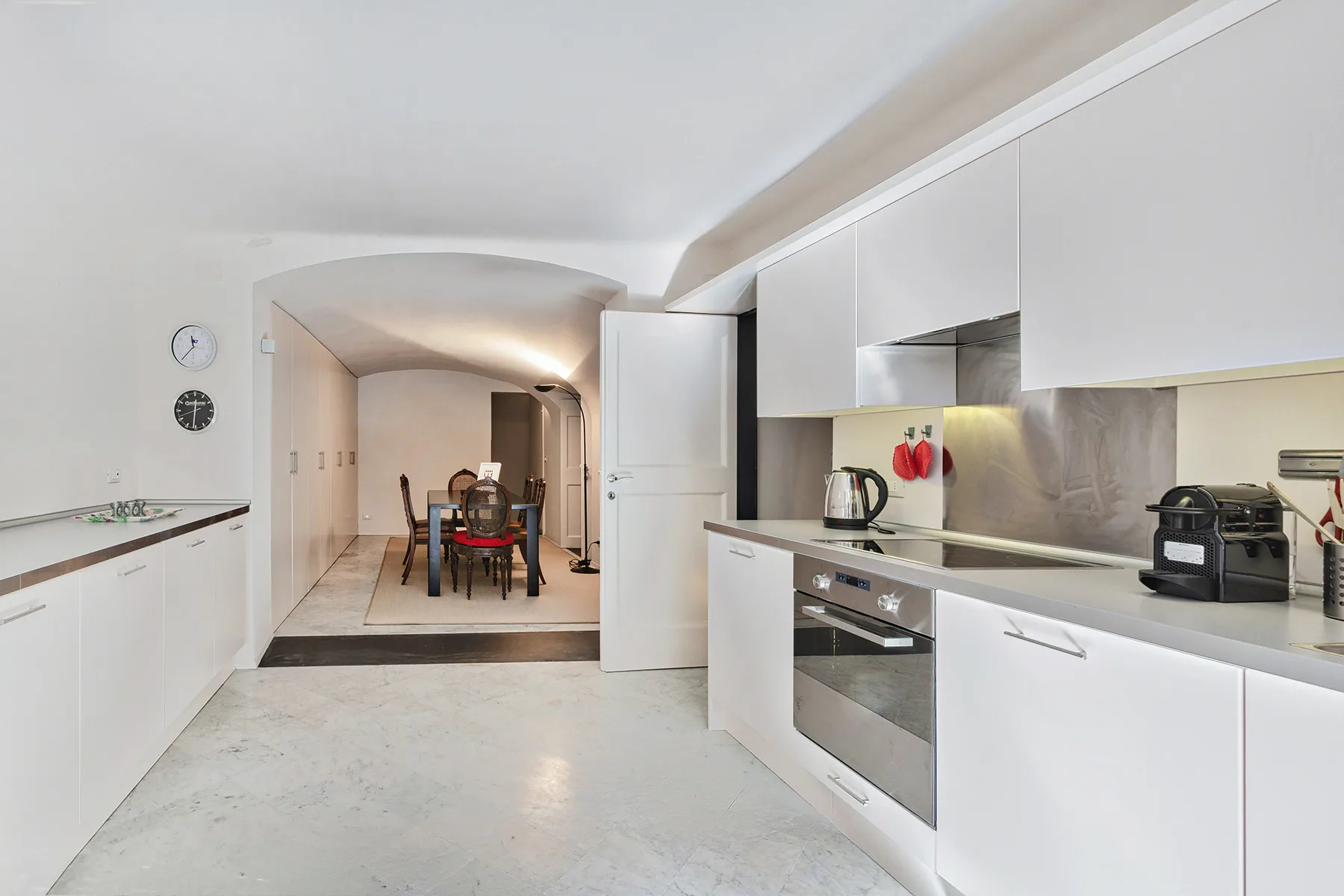 Una cocina luminosa se abre a un comedor con mesa y sillas.