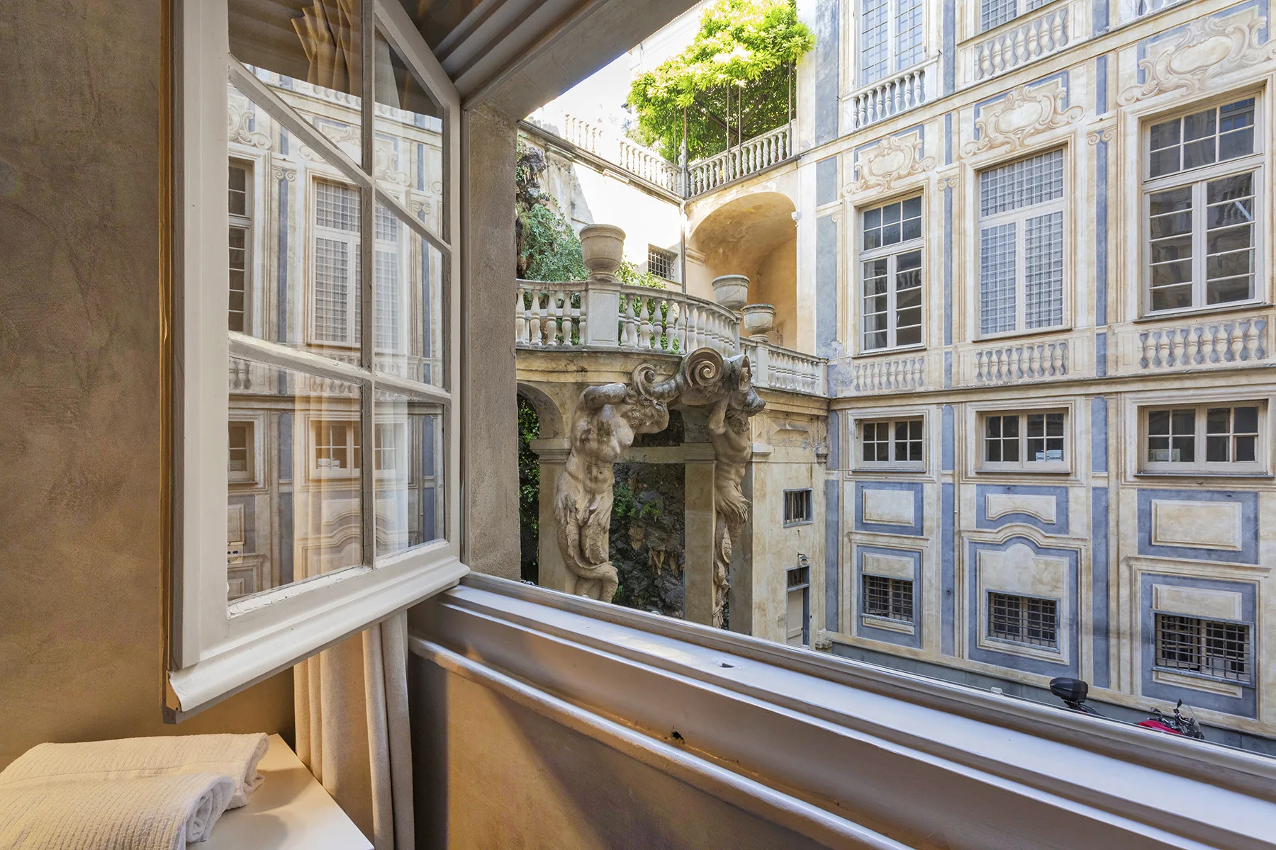 Una ventana abierta da a un patio ornamentado con detalles de piedra.